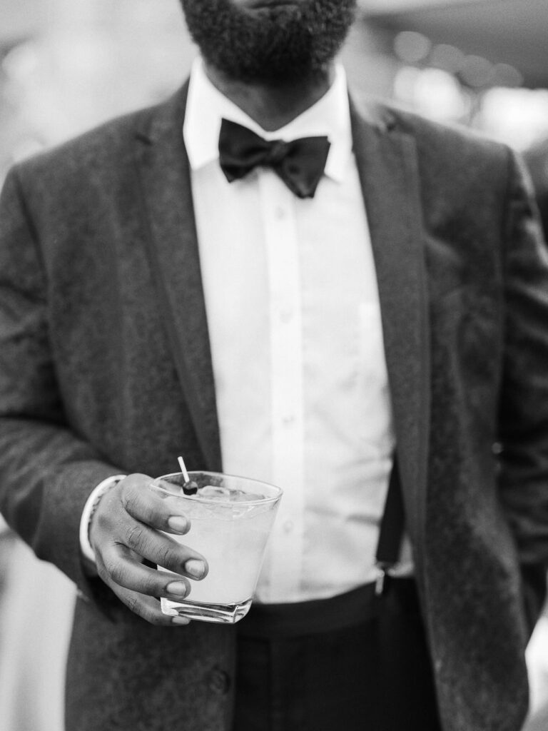 Guest in tuxedo holding cocktail editorial wedding photo