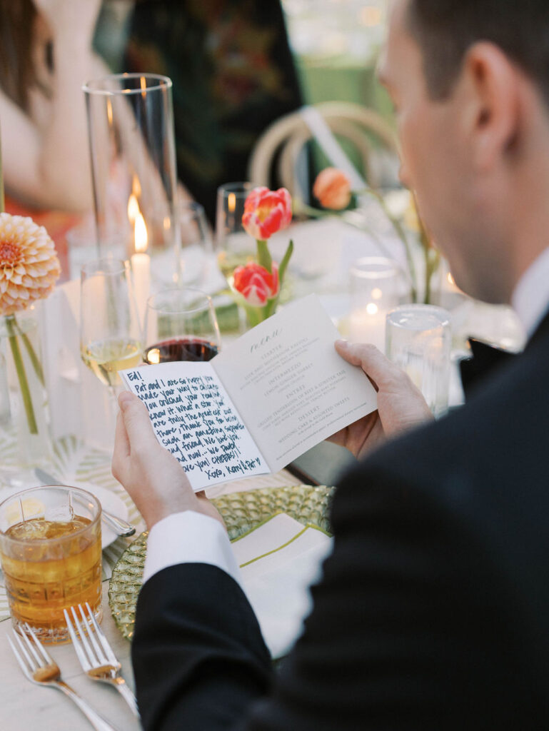 Groom reading vows during wedding reception dinner