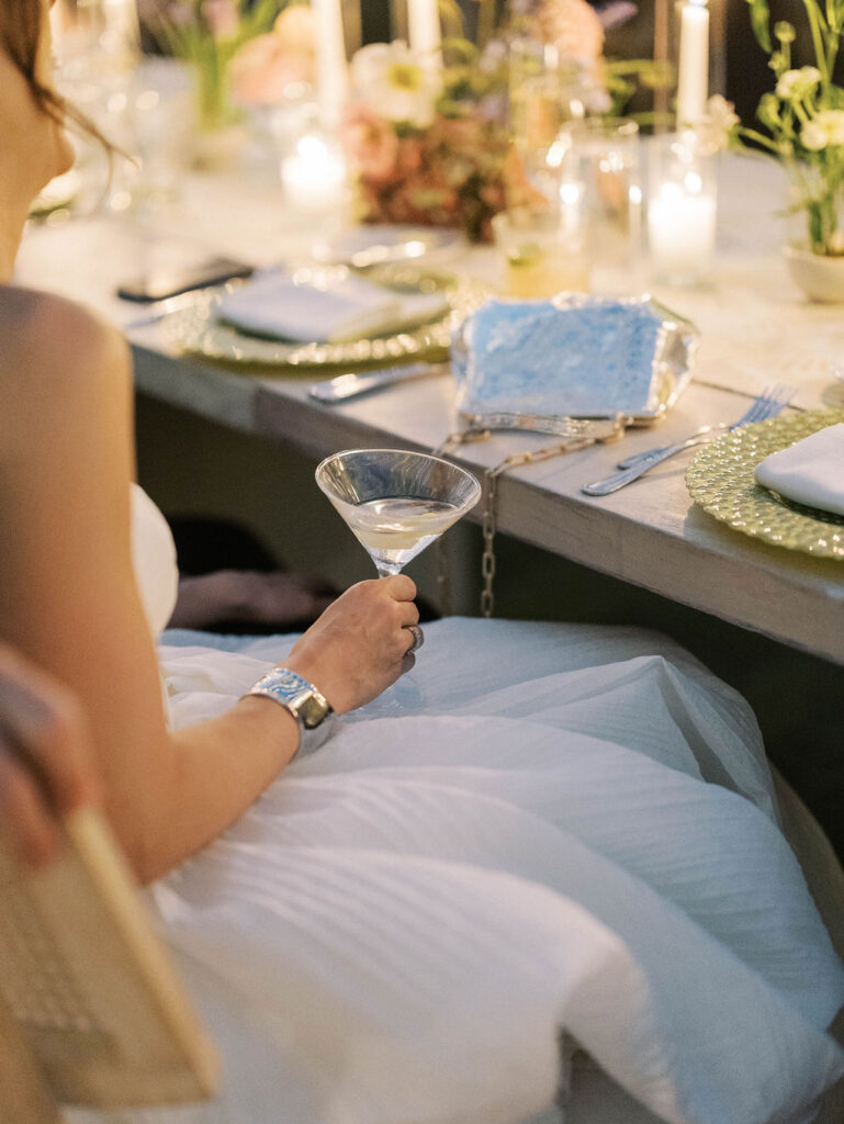 Bride holding martini at elegant wedding dinner reception