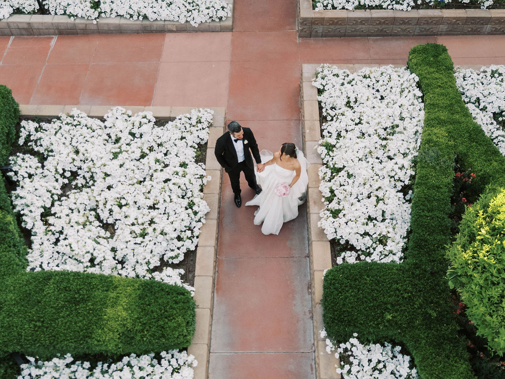 Bride and groom walking down flower-lined path at Arizona wedding