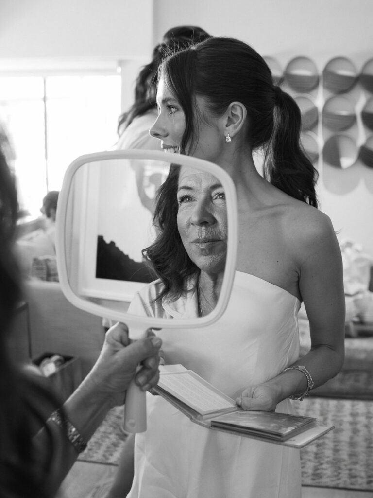 Bride getting ready with mother reflection in mirror