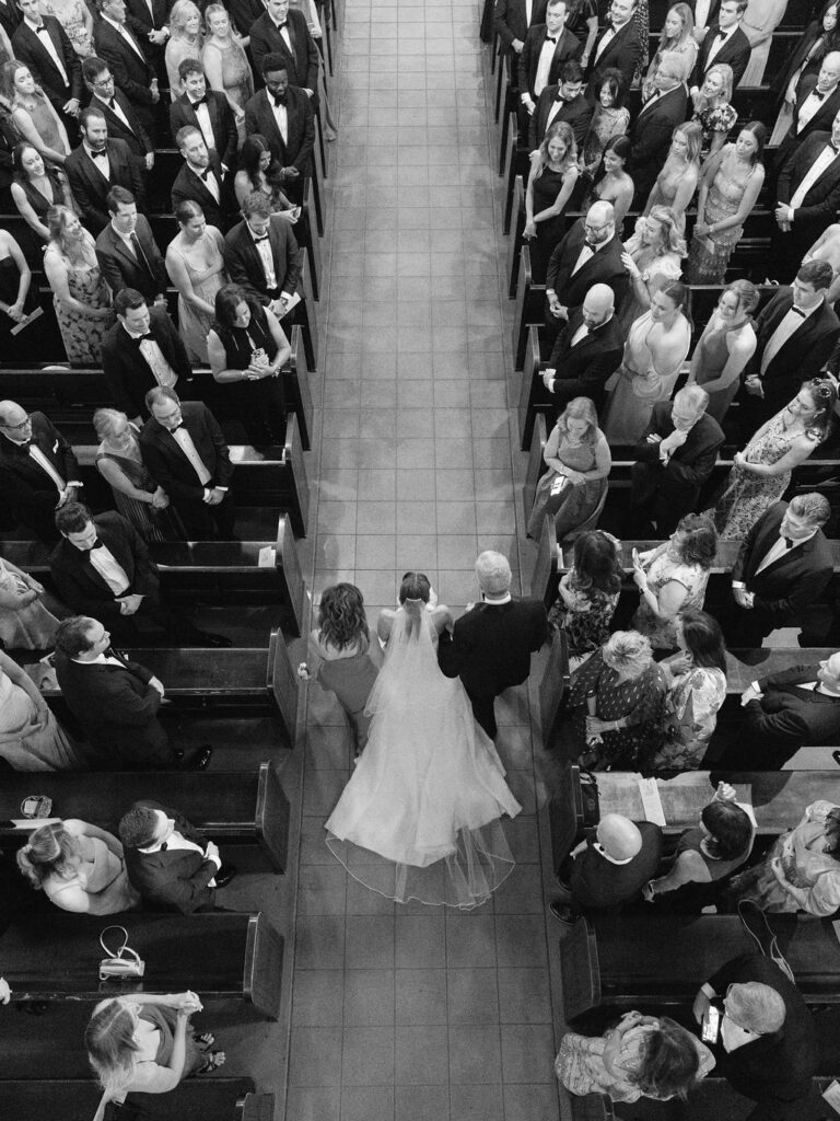 Black and white ceremony photo bride walking aisle