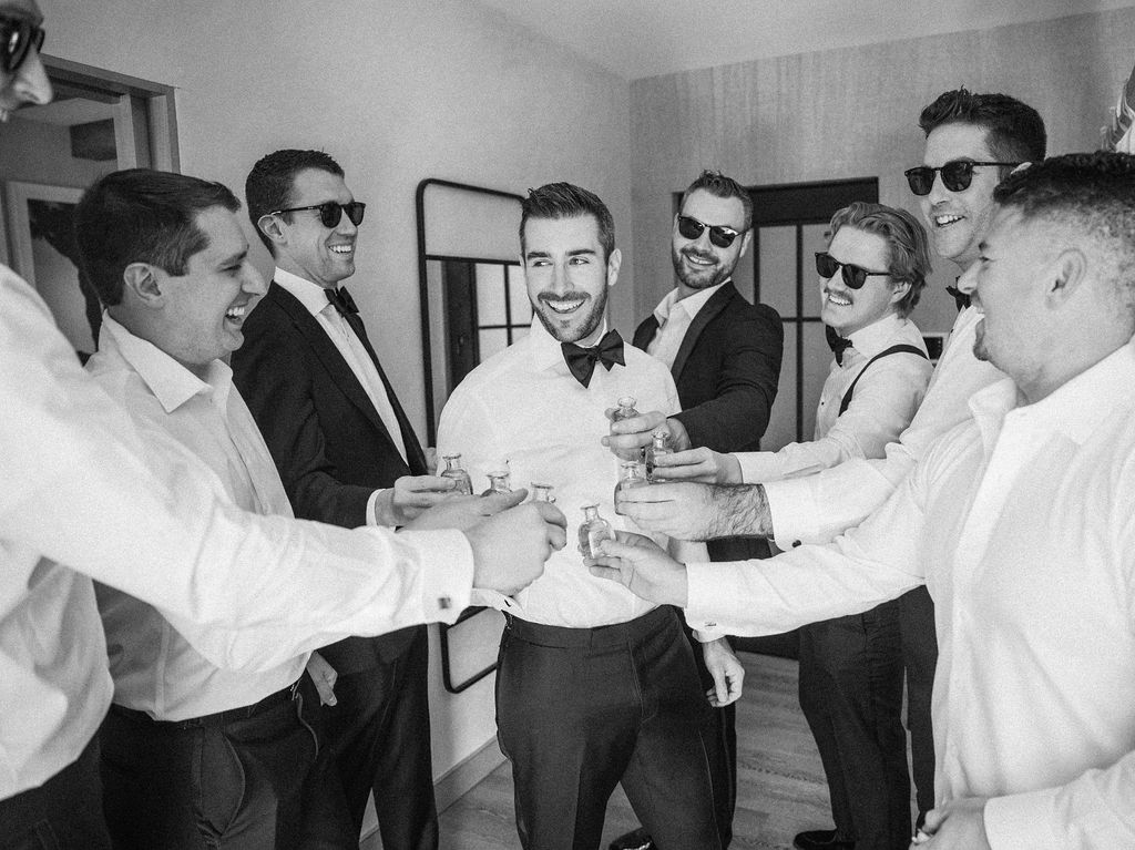 Groom and groomsmen toast with cocktails before wedding ceremony