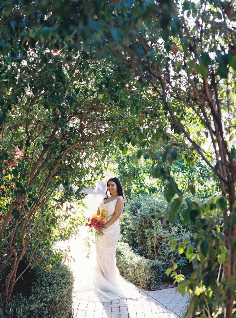 Bride holding bouquet under floral archway at El Chorro.
