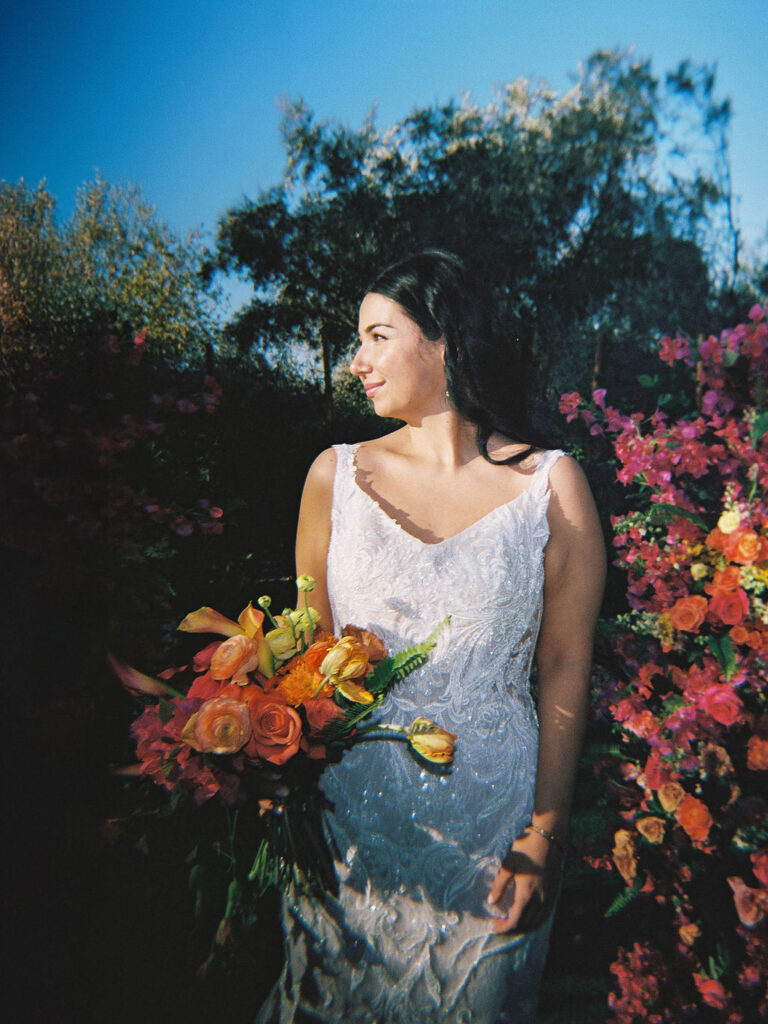 Bride smiling in garden setting holding colorful bouquet at El Chorro.