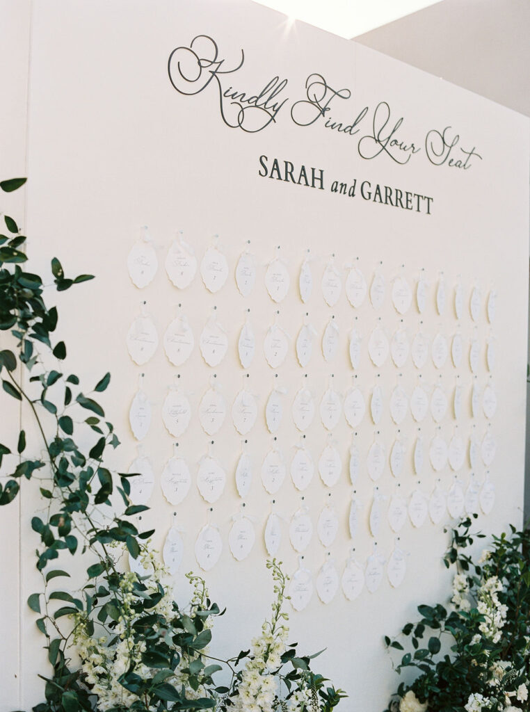 Wedding seating chart display with greenery detail.