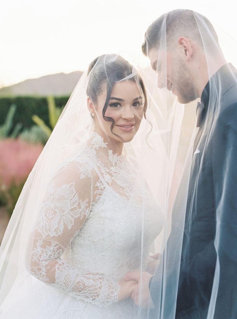 Bride smiling under her veil during outdoor Arizona wedding ceremony.