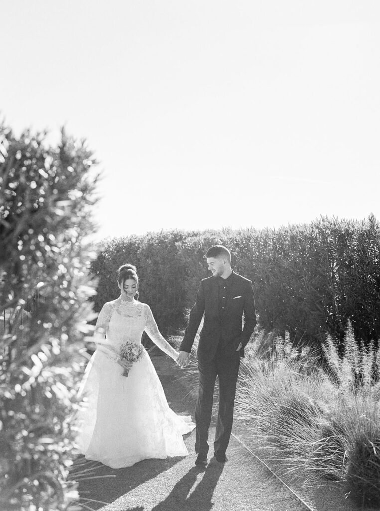 Bride and groom holding hands outdoors in black and white.