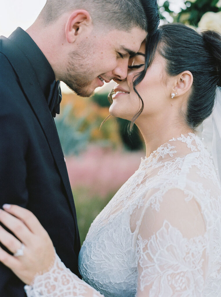 Bride and groom touching foreheads in romantic portrait.