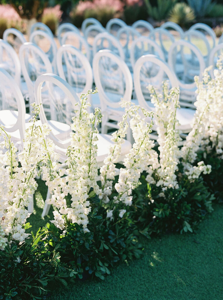 White floral arrangements decorating elegant ceremony seating.