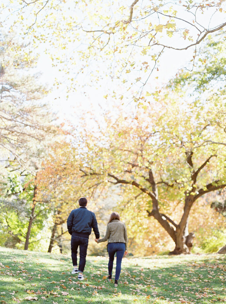 Couple walking hand-in-hand through Central Park during NYC fall engagement