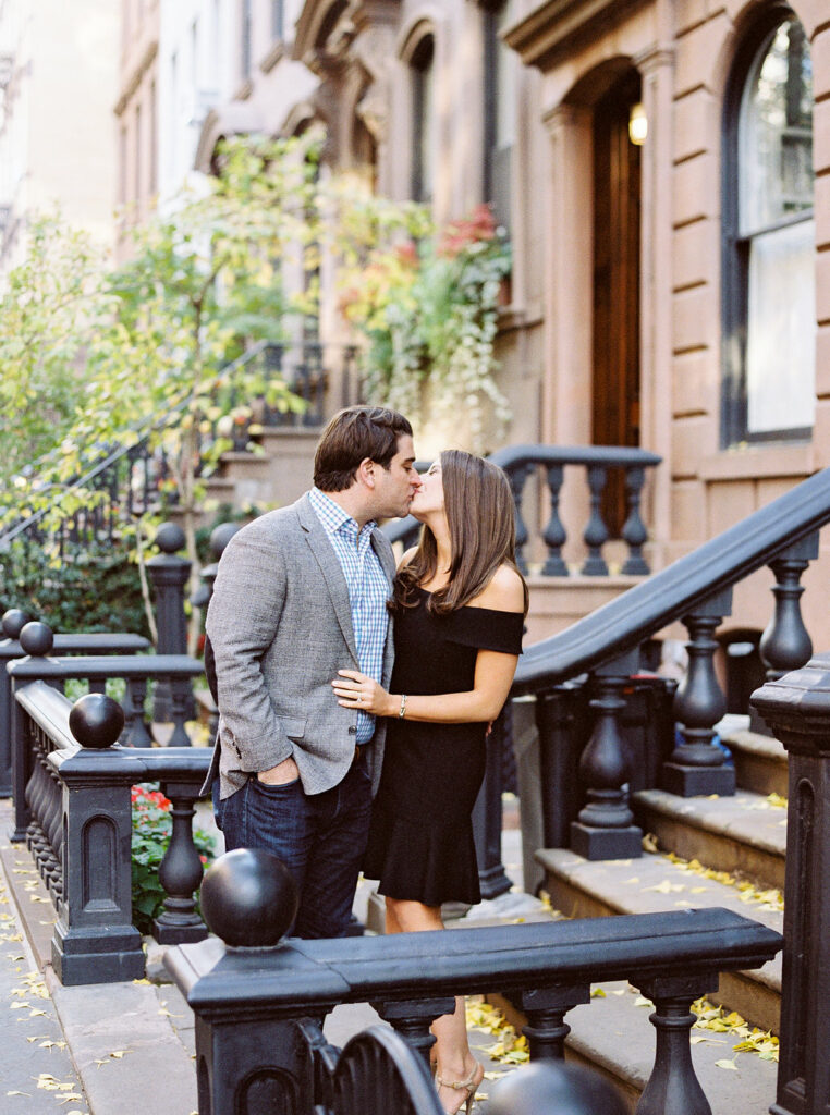 Couple kissing on historic West Village brownstone stoop during engagement session