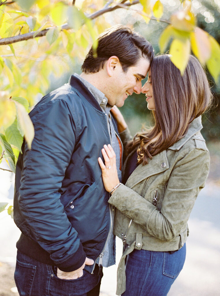 Intimate NYC fall engagement portrait surrounded by golden leaves