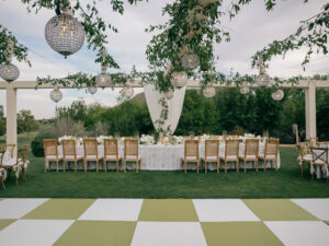 Outdoor reception table with hanging lanterns and greenery.