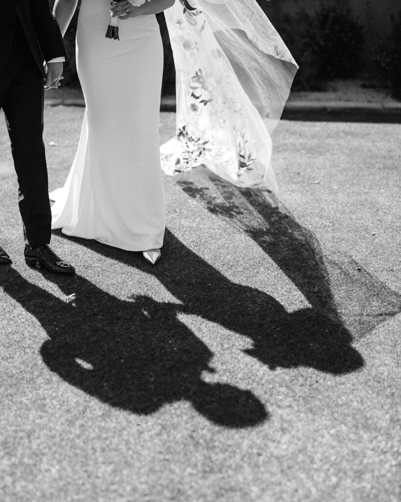 Bride and groom walking with shadows cast on the ground