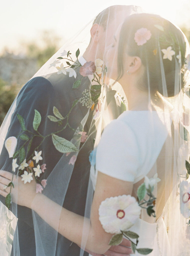 Bride and groom kissing under veil in Arizona sunlight