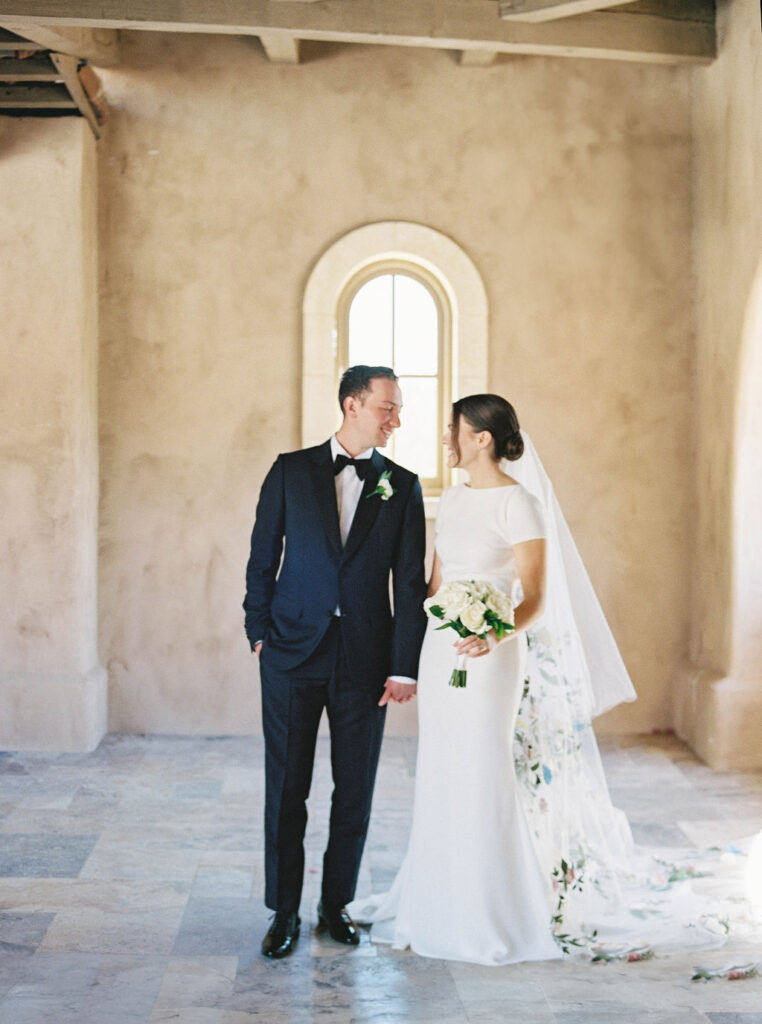 Bride and groom smiling under stone arch at DC Ranch wedding