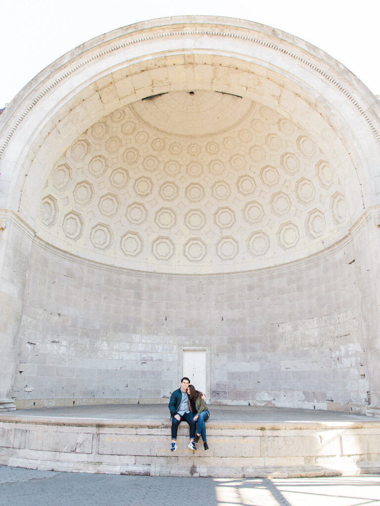Couple sitting together at Naumburg Bandshell during NYC fall engagement session