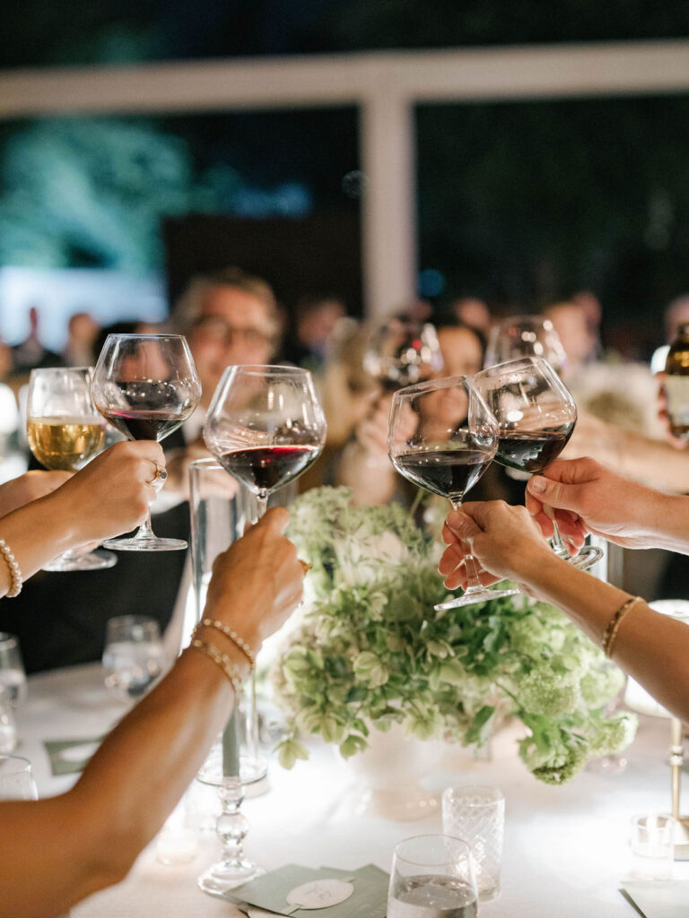 Guests raising wine glasses at outdoor wedding reception.