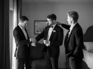 Groomsmen adjusting suits before ceremony in black and white.