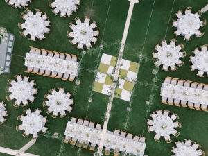 Aerial view of reception setup with checkerboard lawn and round tables.