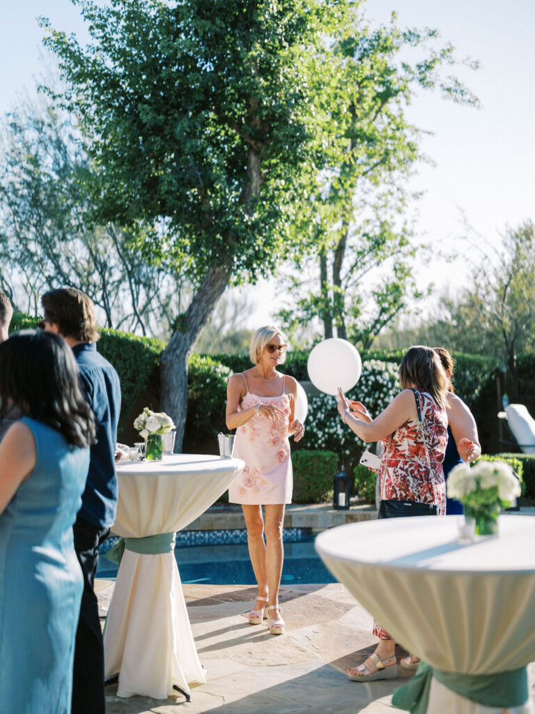Guest in floral dress by cocktail table at Silverleaf Arizona wedding welcome party