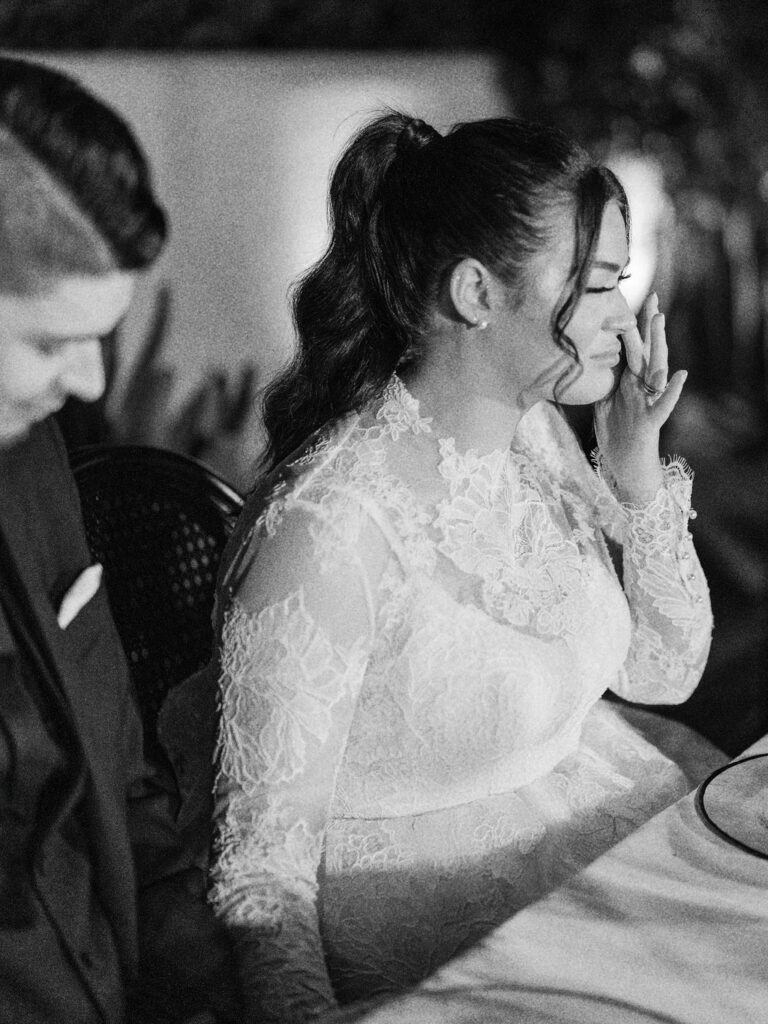 Bride in lace gown laughing during dinner, captured by documentary wedding photographer in Arizona.