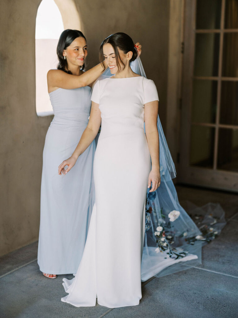 Bridesmaid adjusting bride’s gown during DC Ranch wedding