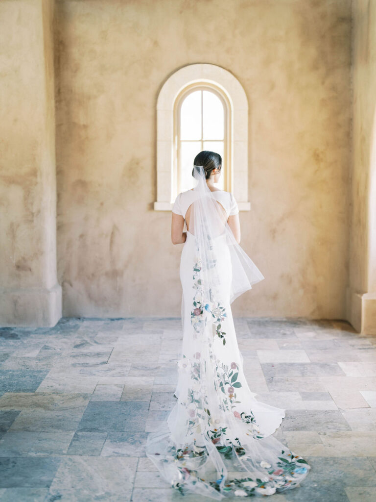 Bride in floral-detailed gown standing in arched room DC Ranch