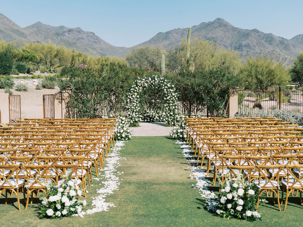 Wedding ceremony aisle with floral arch and desert mountains