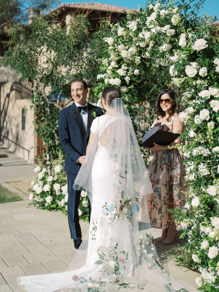 Couple exchanging vows under floral arch at DC Ranch wedding