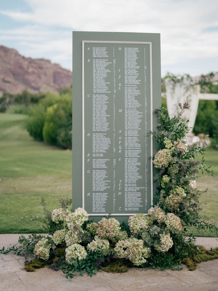 Green wedding seating chart displayed on lawn with Camelback Mountain.