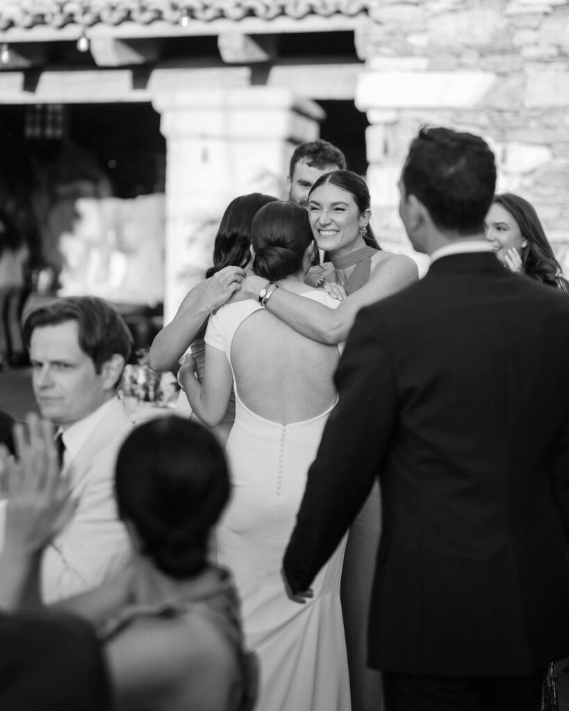 Bride hugging friends during candid wedding reception moment