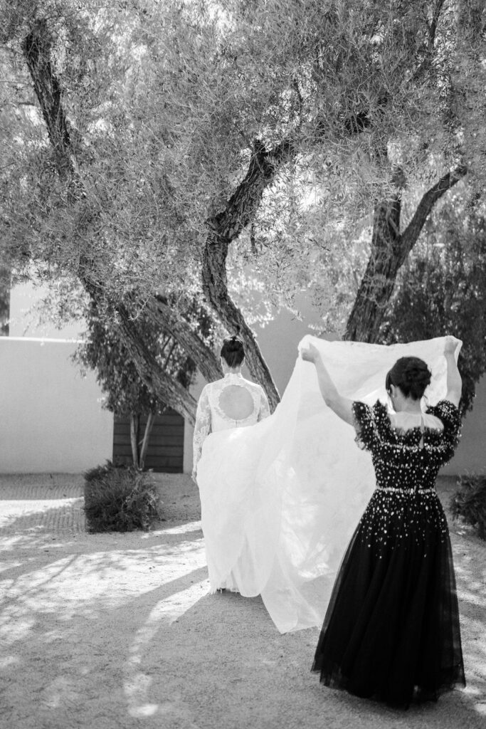 Bridesmaids adjusting bride’s veil in black and white.
