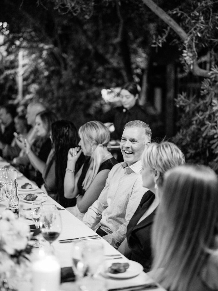 Black and white candid of guests laughing at El Chorro dinner table