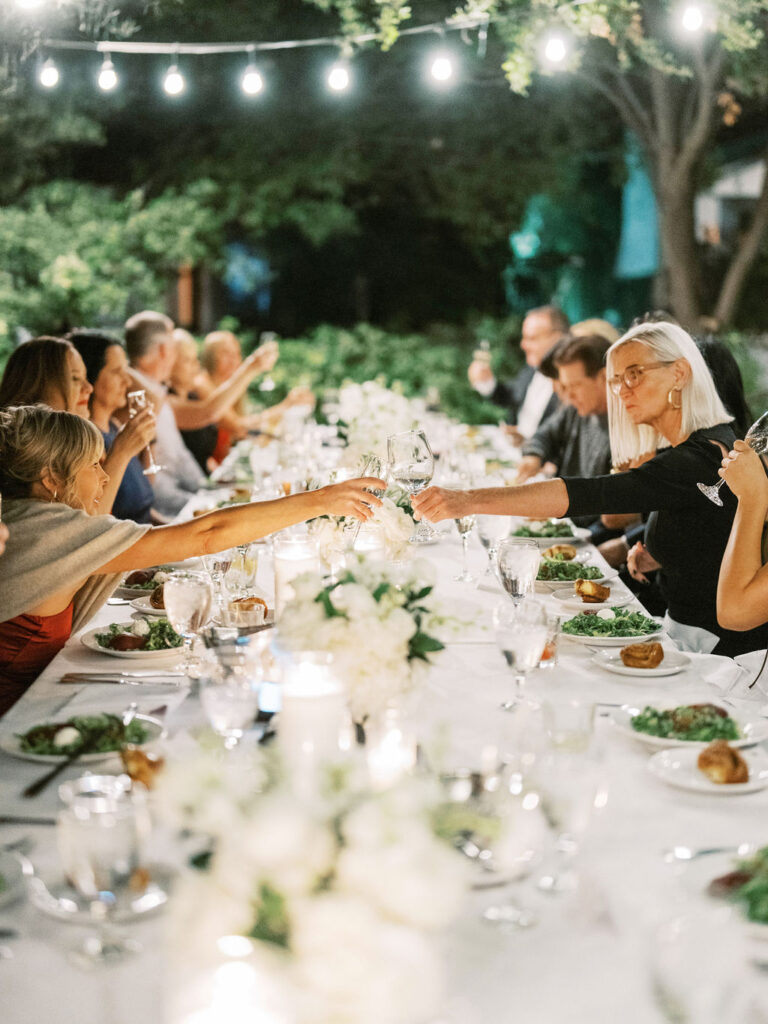 Guests raising glasses at long dinner table El Chorro party
