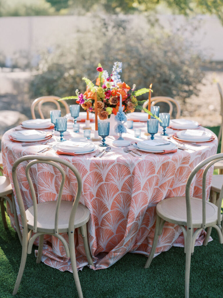 Round reception table with coral linens and colorful florals at El Chorro.
