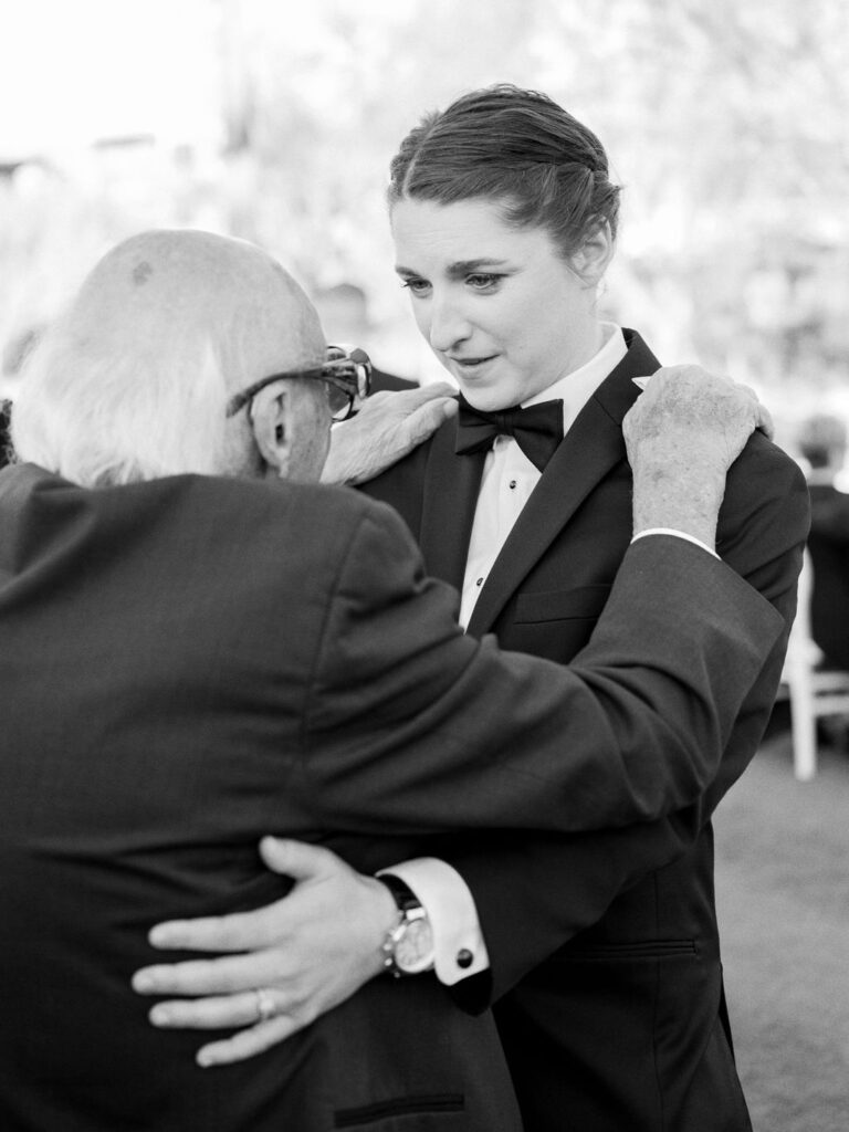 Groom hugging older family member during Arizona wedding, black and white.