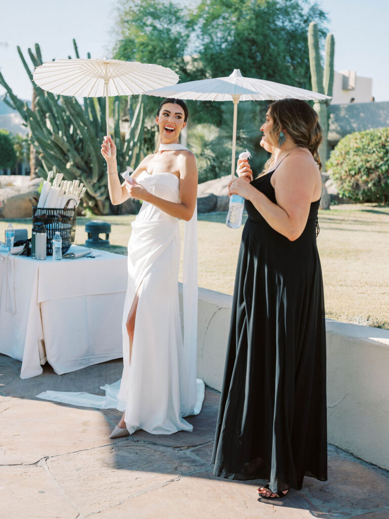 Bride with a white parasol chatting with guests at Camelback Inn