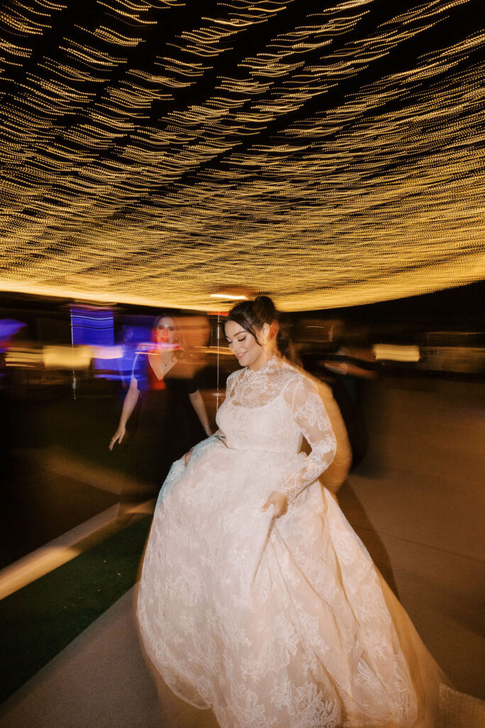 Bride twirling in gown at reception with artistic motion blur.