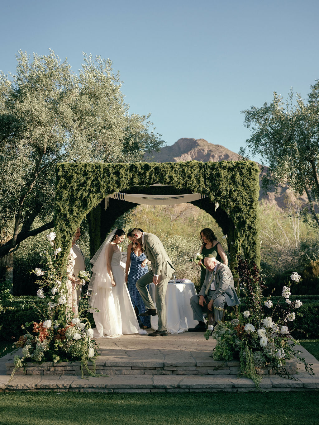 Groom breaking the glass at the end of the ceremony as the bride and family look on