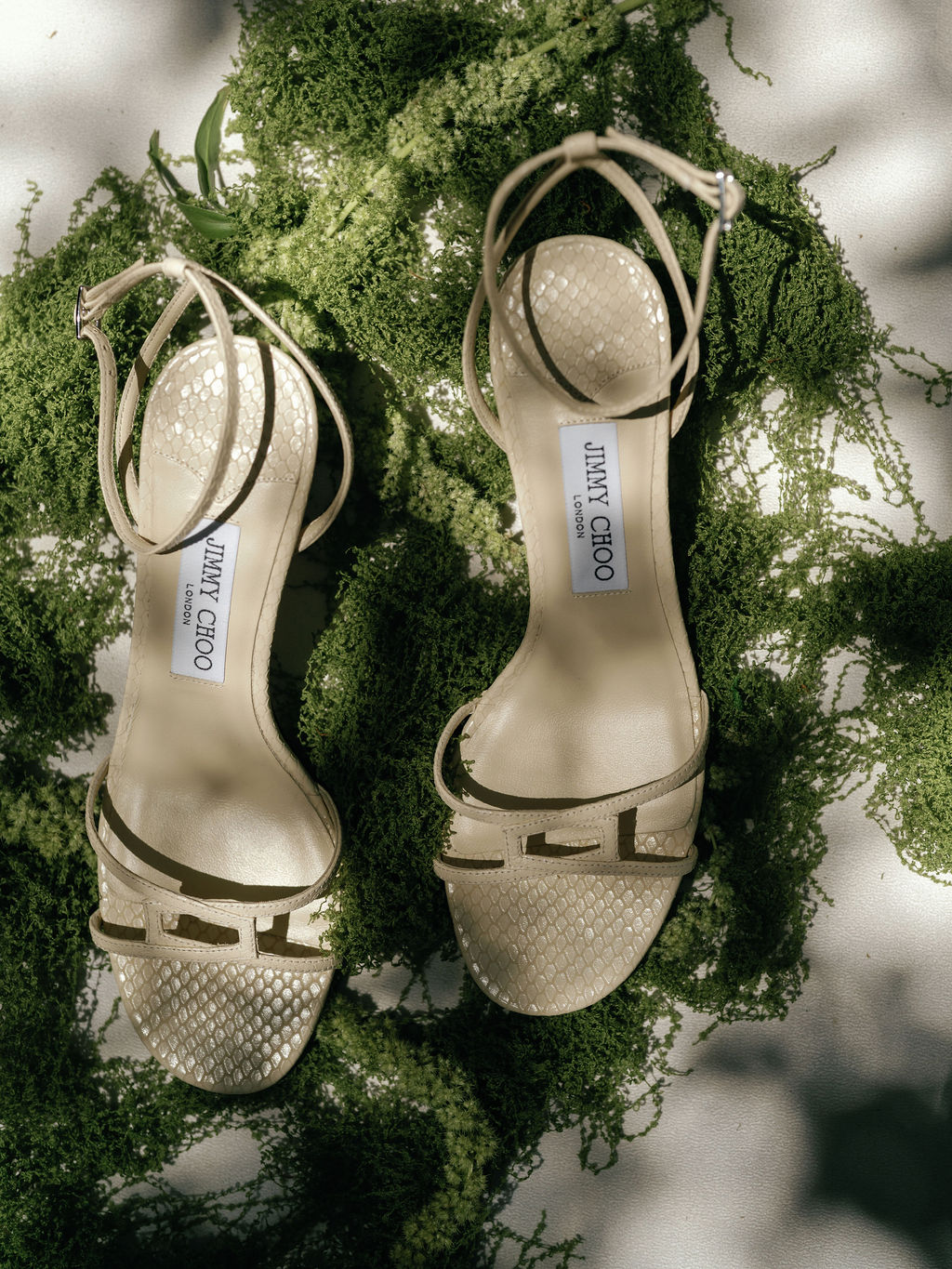 Bride's heels resting on the moss beneath the ceremony arch