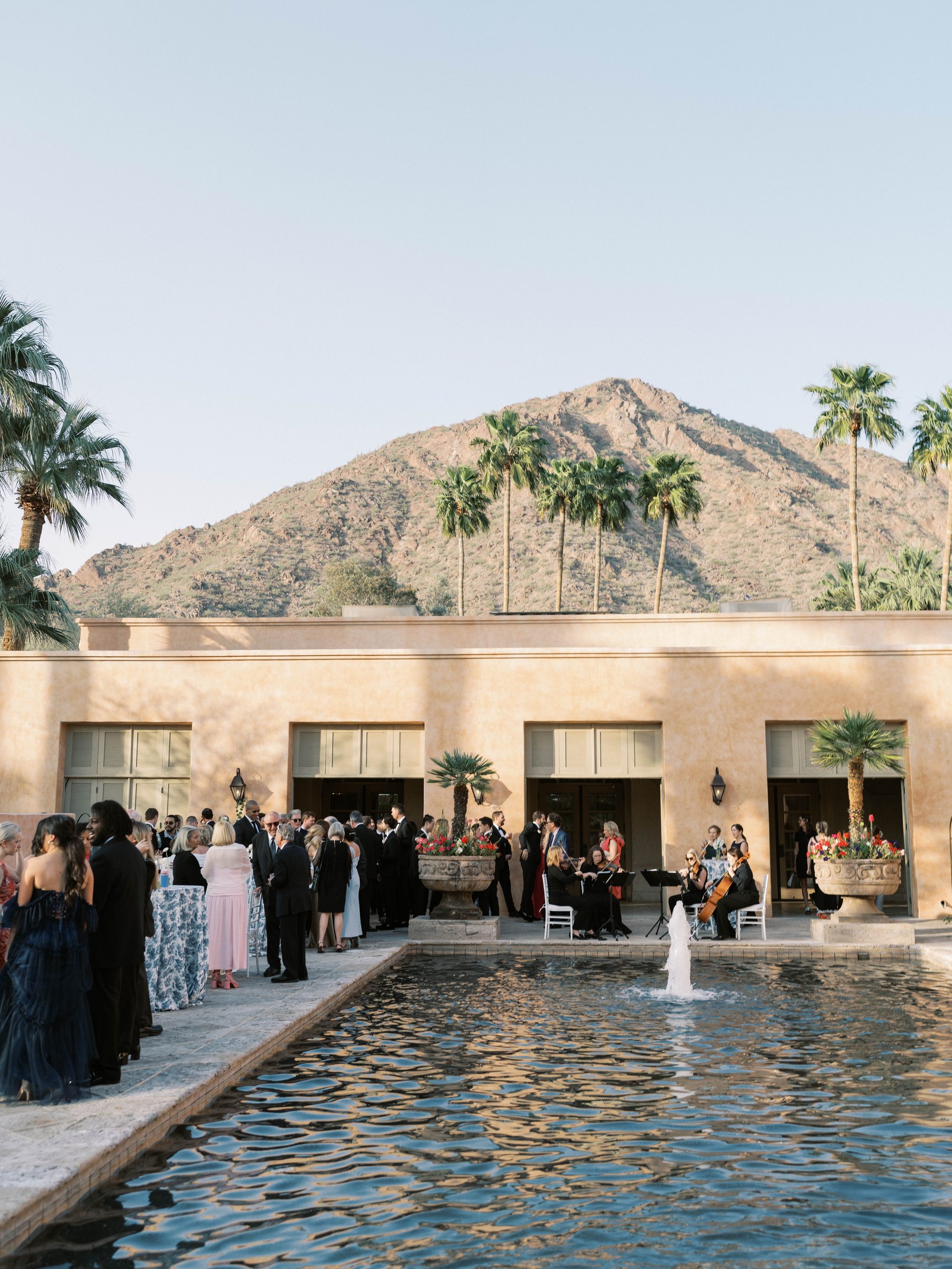 Wedding guests gather beside the reflecting pool with Camelback Mountain beyond