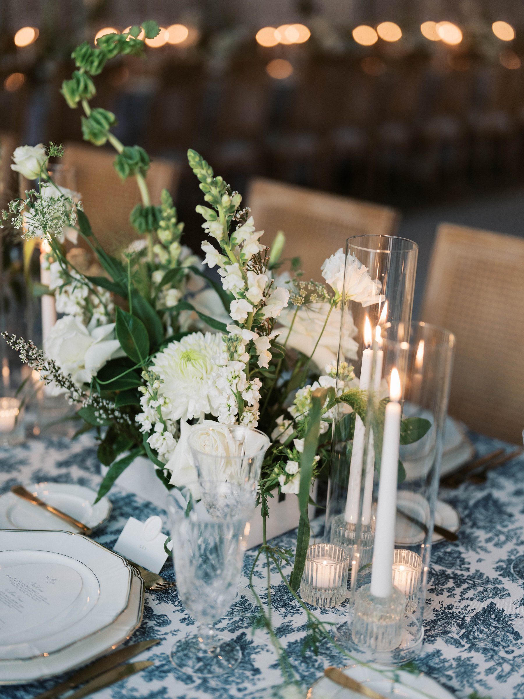 White florals and candles on a blue toile dinner table