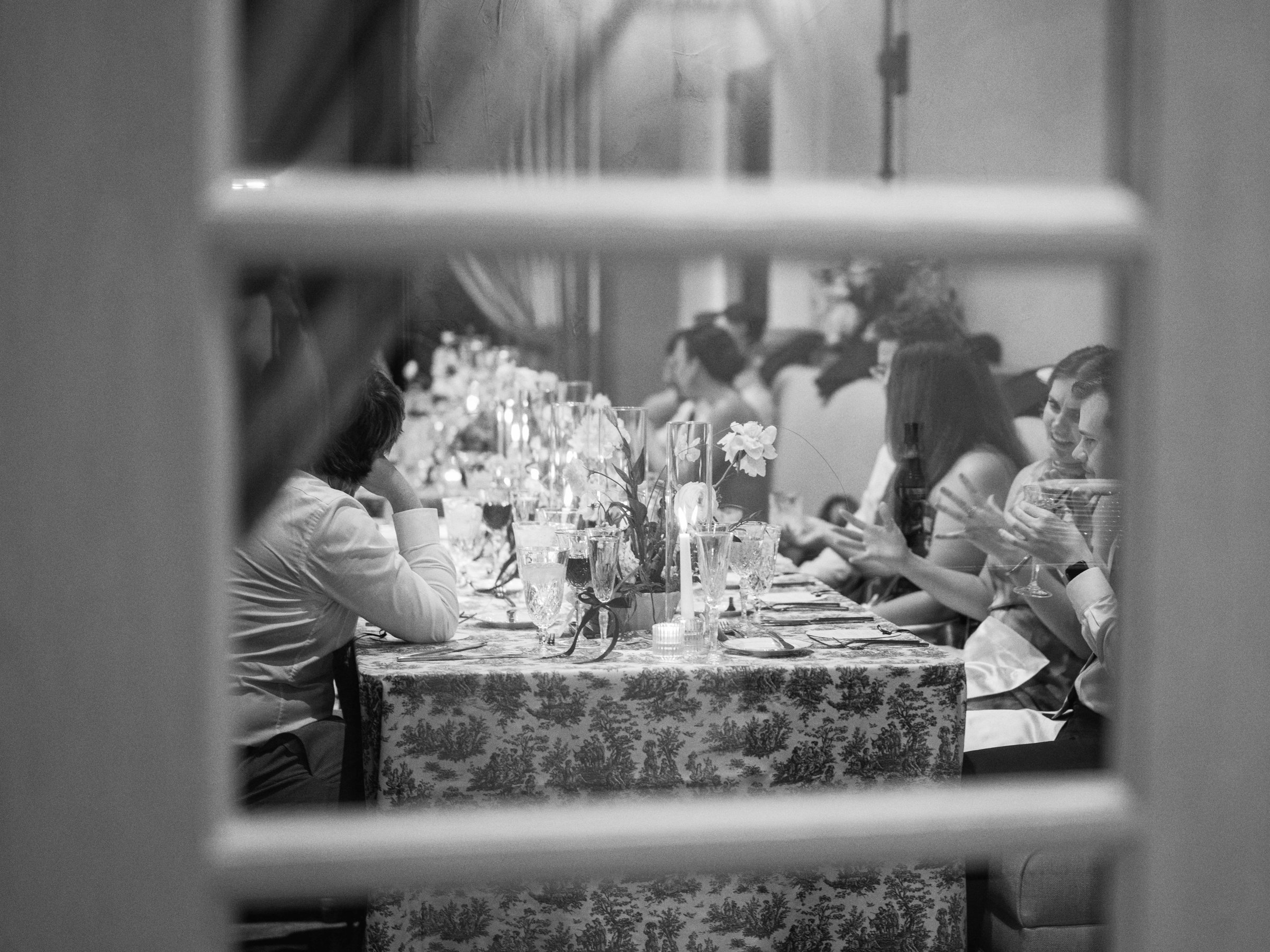 Wedding guests seen through a window at the candlelit reception