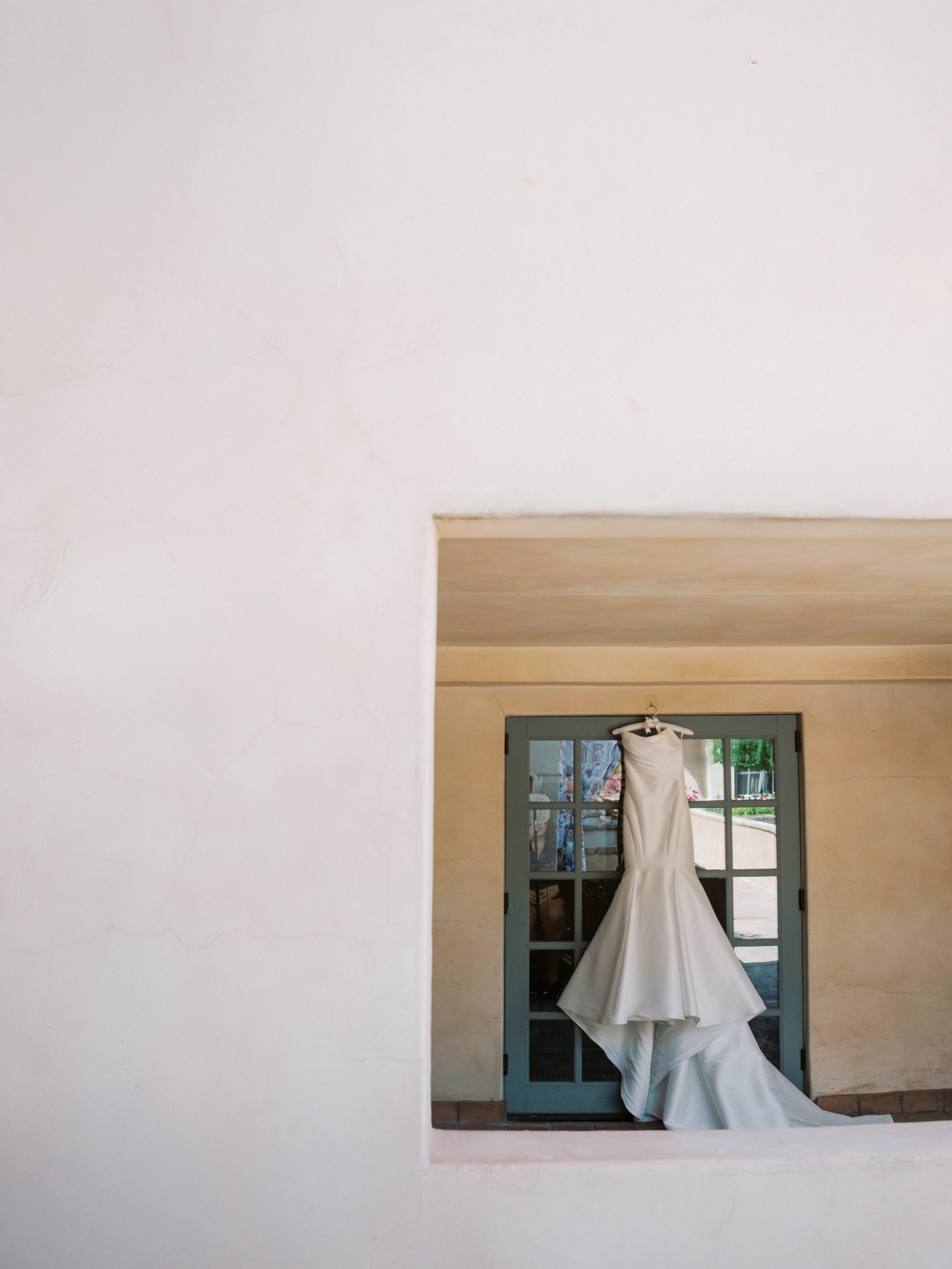 Meg’s wedding gown framed by an archway and blue doors at Royal Palms