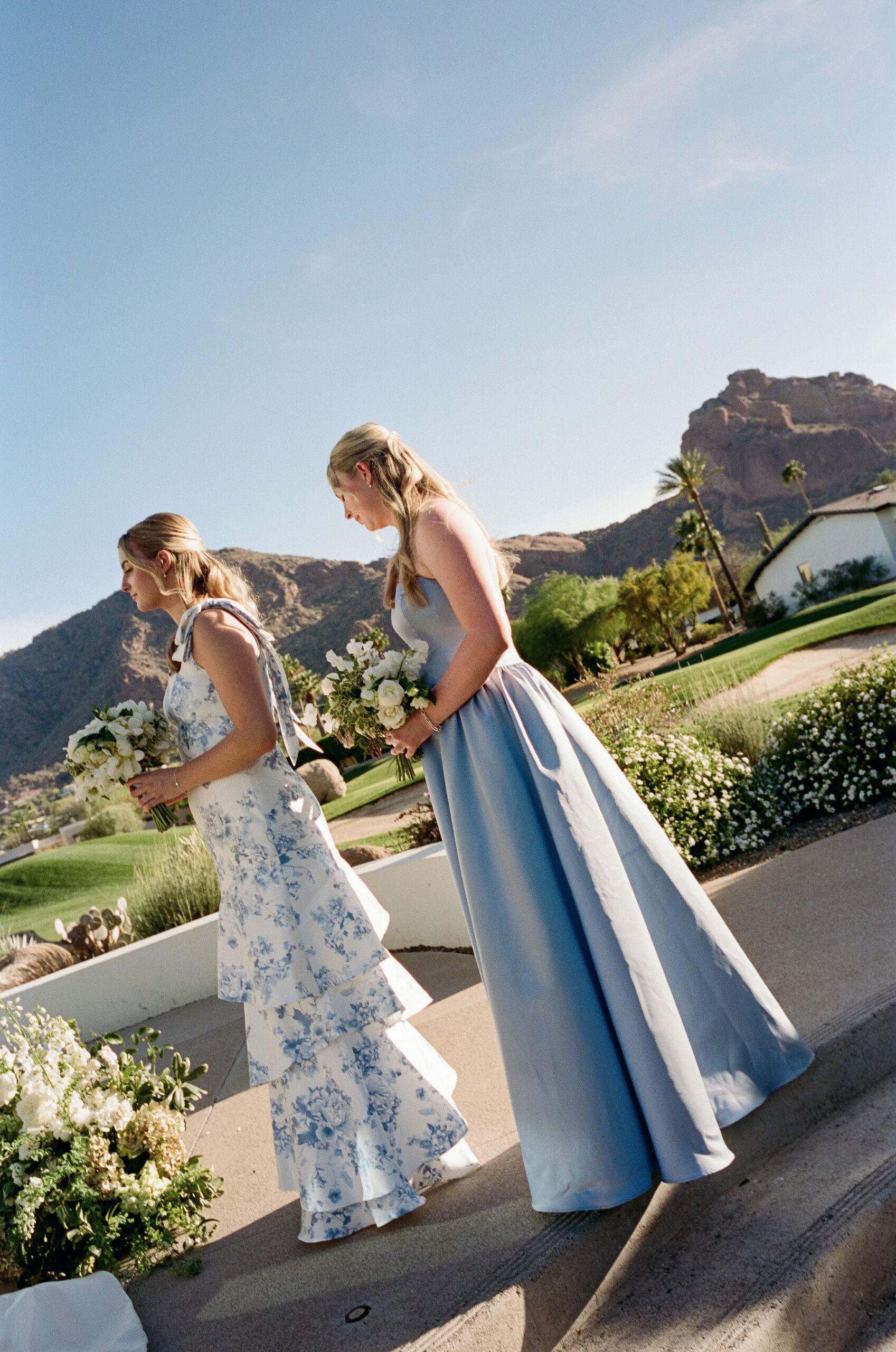 Bridesmaids crossing the curved ceremony steps with mountain views on film.