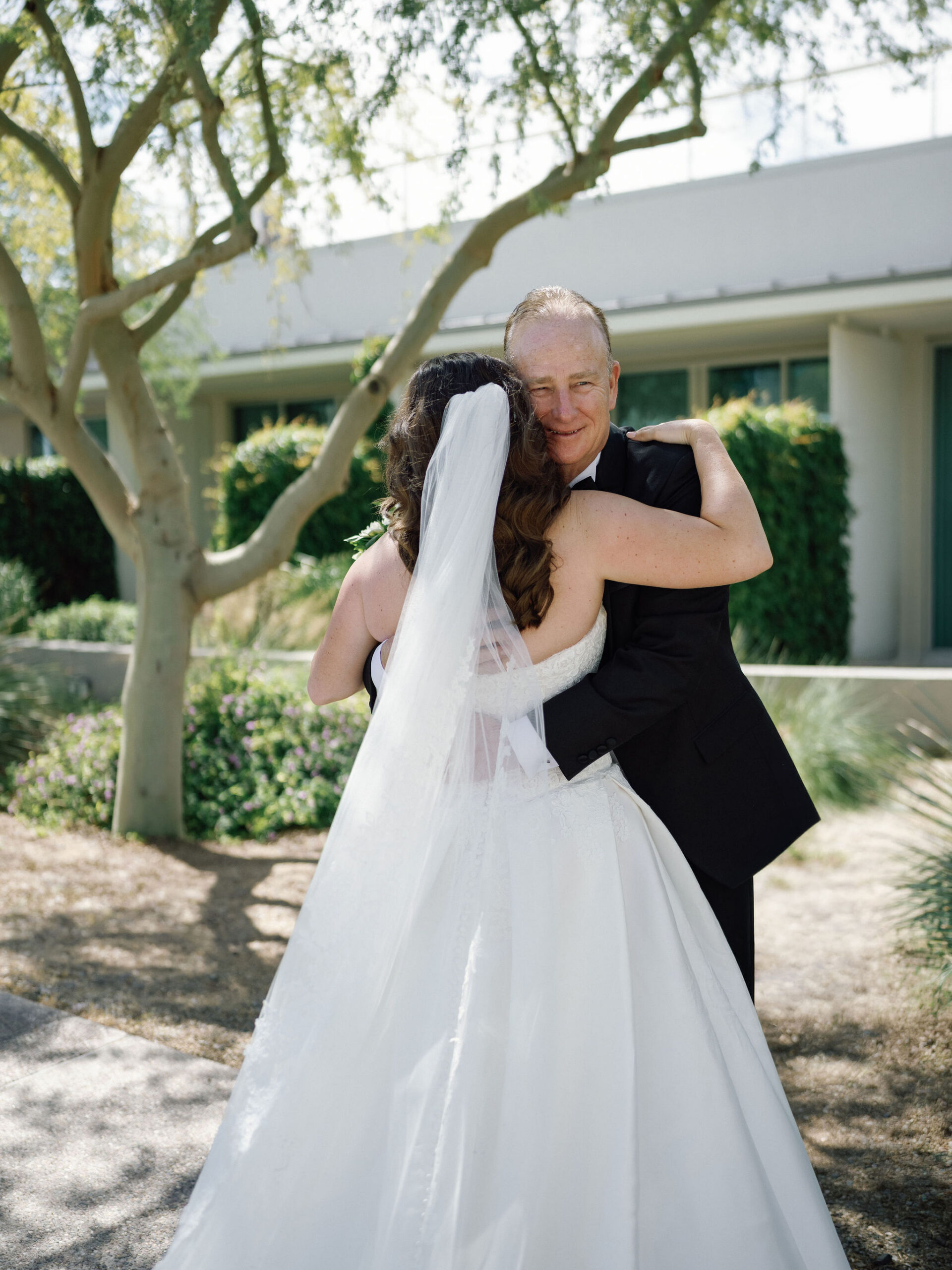 Taylor embracing her father beneath a tree before the ceremony.