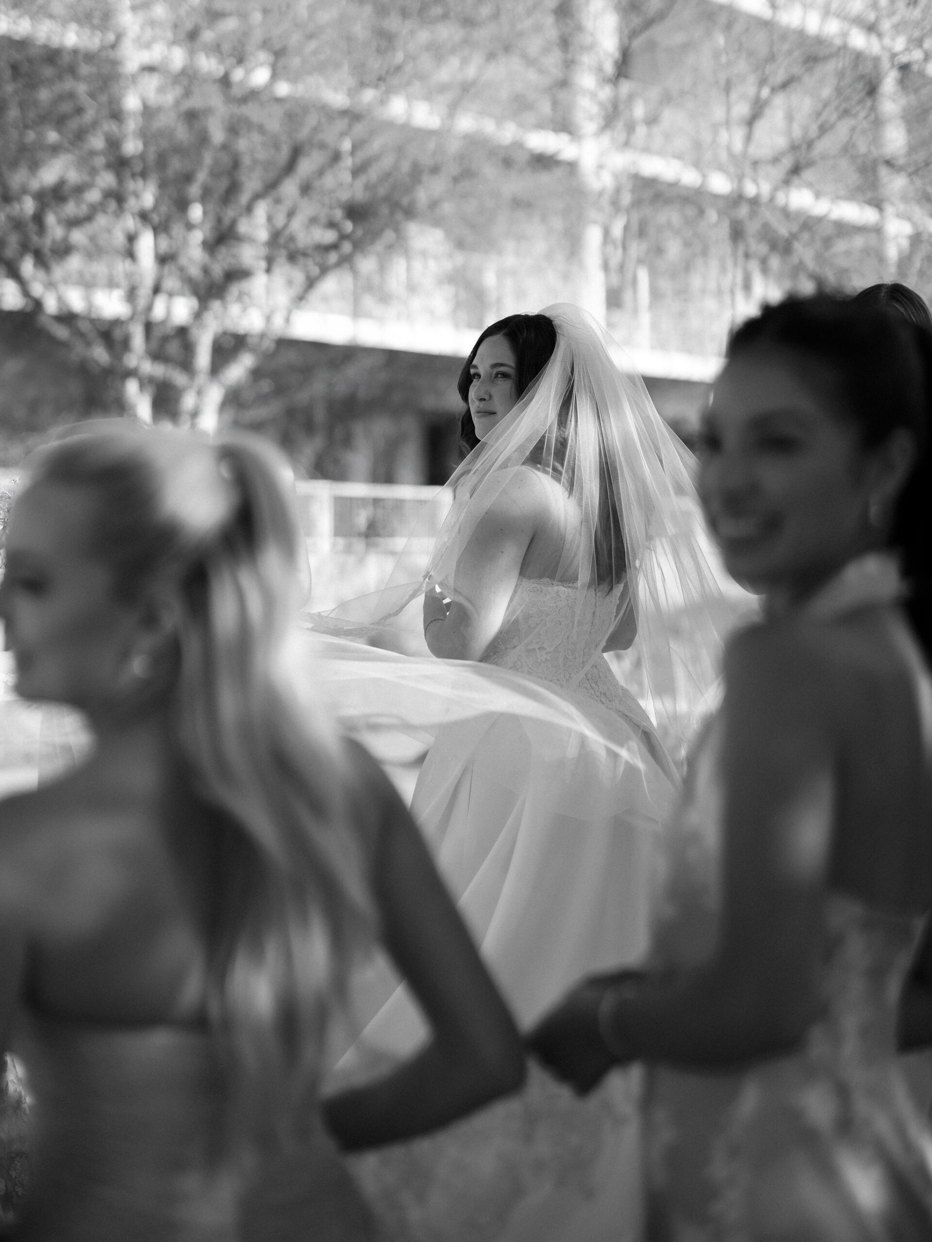 Taylor seen through her veil and the softly blurred figures of her bridesmaids.