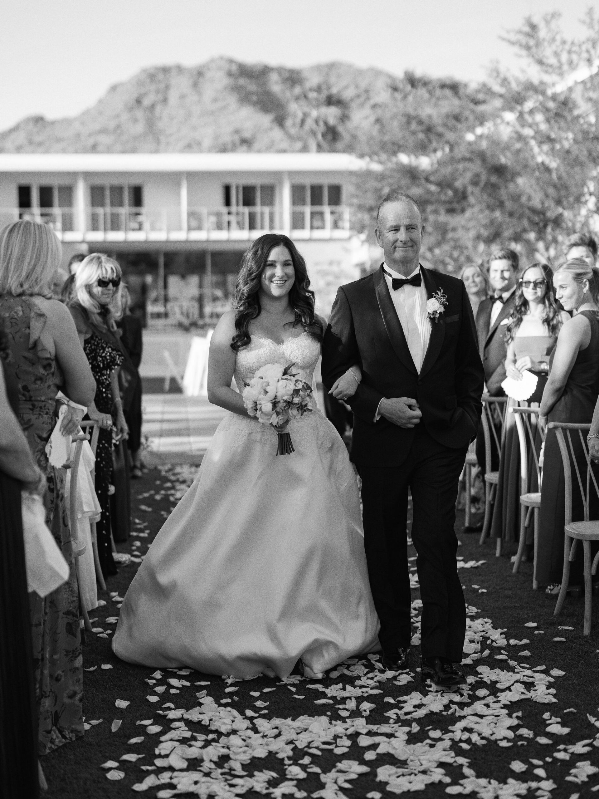 Taylor and her father walking down the aisle in black and white.